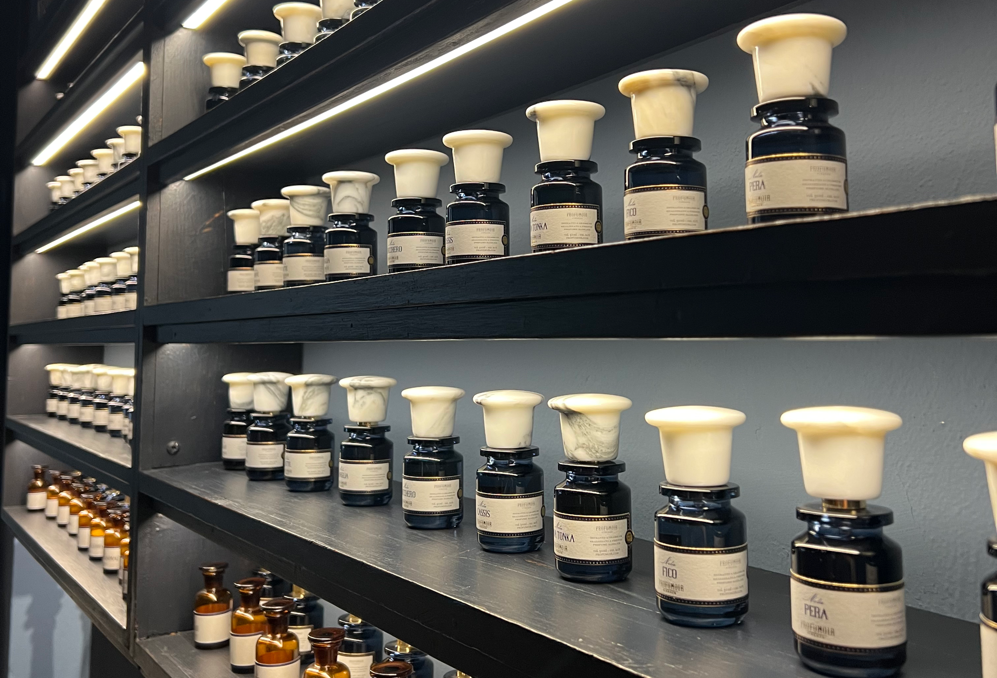 Reihen an Duftflakons, beleuchtet, in Regalen aufgestellt 